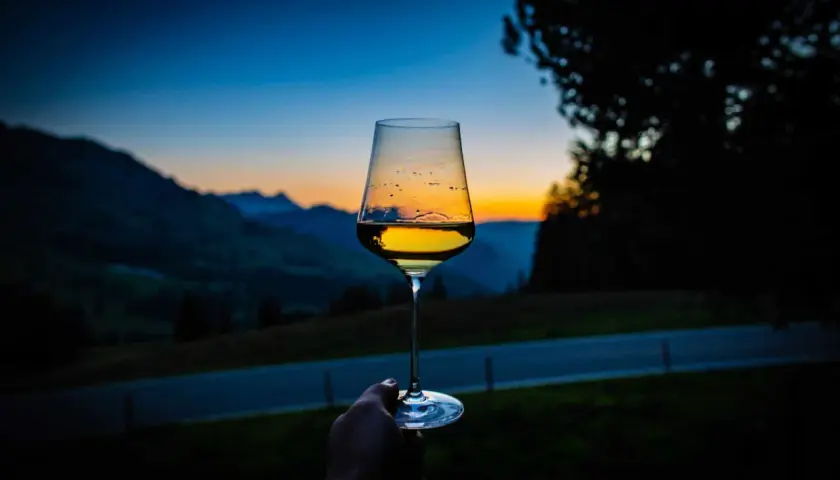 Un calice di vini aromatici riflette il tramonto sulle montagne.