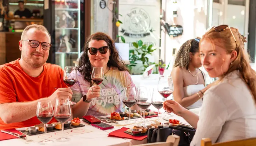 Amici brindano a una degustazione vini a Pisa, assaporando sapori toscani con un bicchiere di rosso.