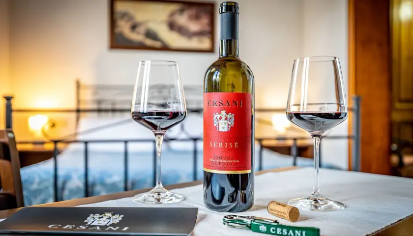 Un calice di vino rosso Cesani, una bottiglia di Serisé Ciliegiolo e un cavatappi, pronti per una degustazione alla Cesani winery.