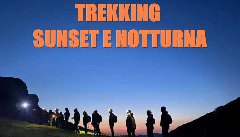 Gruppo di escursionisti al tramonto e di notte al passo dell'Abetone, con luci frontali accese.