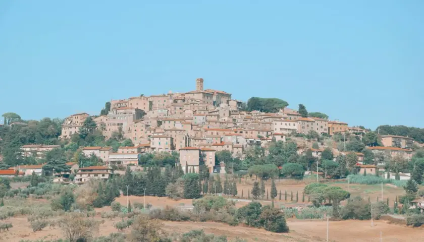 Panoramica di Casale Marittimo, un borgo medievale toscano arroccato su una collina, con case in pietra e tetti rossi, circondato da ulivi e cipressi.
