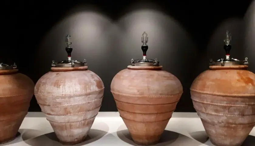 Quattro anfore in terracotta, con tappi metallici e gorgogliatori, pronte per la fermentazione del vino.