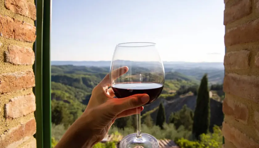 Un bicchiere di vino rosso, con il paesaggio del Val d'Orcia sullo sfondo. Un momento di puro piacere.