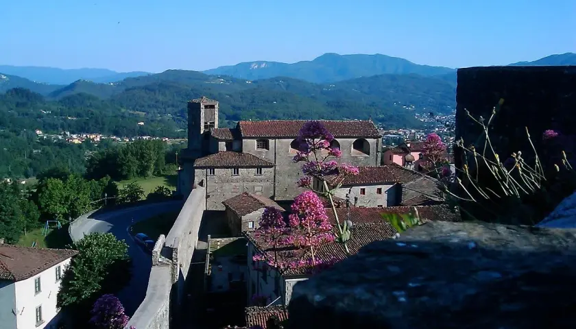 Panoramica di Castiglione di Garfagnana con il suo castello, le case con i tetti rossi e le montagne verdi sullo sfondo.