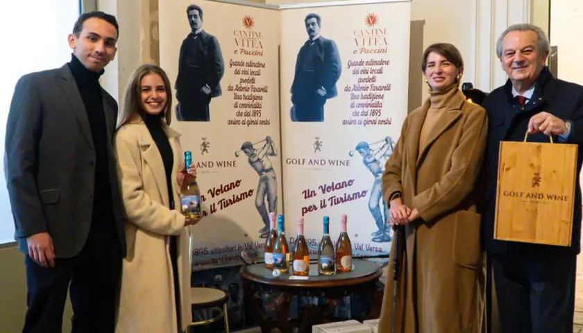 Antonio Faravelli, un nome legato alla tradizione vinicola. Quattro persone sorridono davanti a banner che celebrano la storia di Cantine Vitea e Puccini.