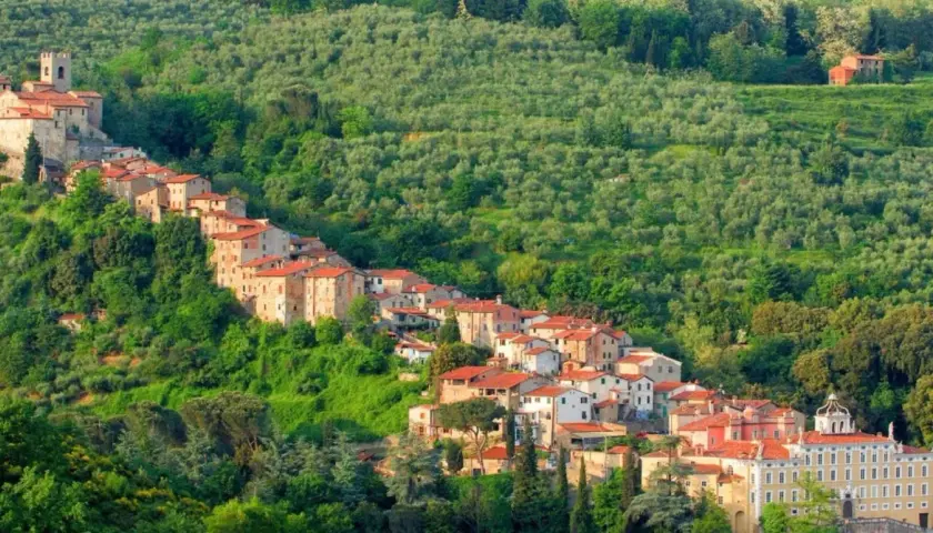 Antichi borghi vicino Pistoia si aggrappano alla collina, circondati da uliveti lussureggianti e vegetazione mediterranea.