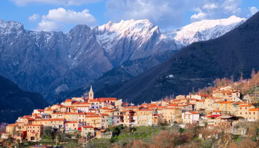 Borgo pittoresco alle pendici delle Alpi Apuane, con case dai tetti rossi e montagne innevate sullo sfondo. Un luogo incantevole da scoprire.