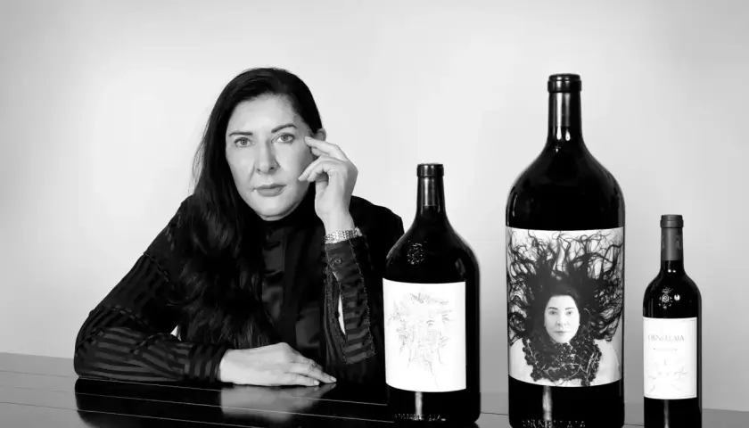 Donna con le migliori annate Ornellaia. Le bottiglie presentano etichette artistiche, una con un ritratto.
