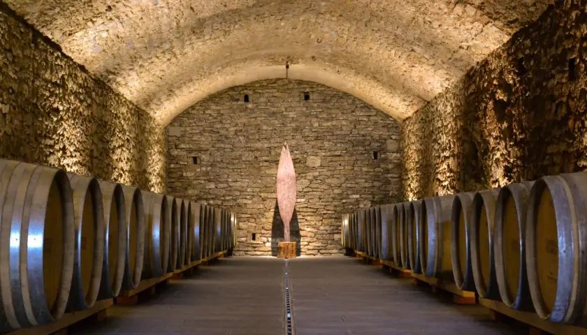 Cantine in pietra con botti di legno, un'installazione artistica al centro. Perfetto per una visita cantine Chianti.