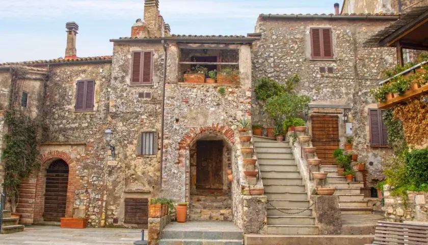 Un pittoresco borgo toscano con case in pietra, scale in terracotta e piante rigogliose.