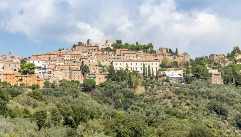 Panoramica di un borgo collinare con case in pietra e tetti rossi, circondato da uliveti. Marina di Campiglia, un gioiello toscano.