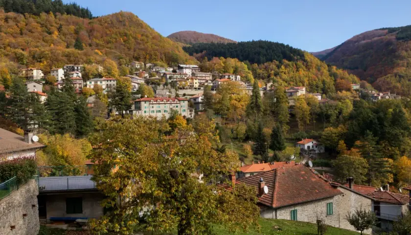 Case colorate e boschi autunnali abbracciano il borgo di Badia Prataglia, un incantevole paesaggio appenninico.