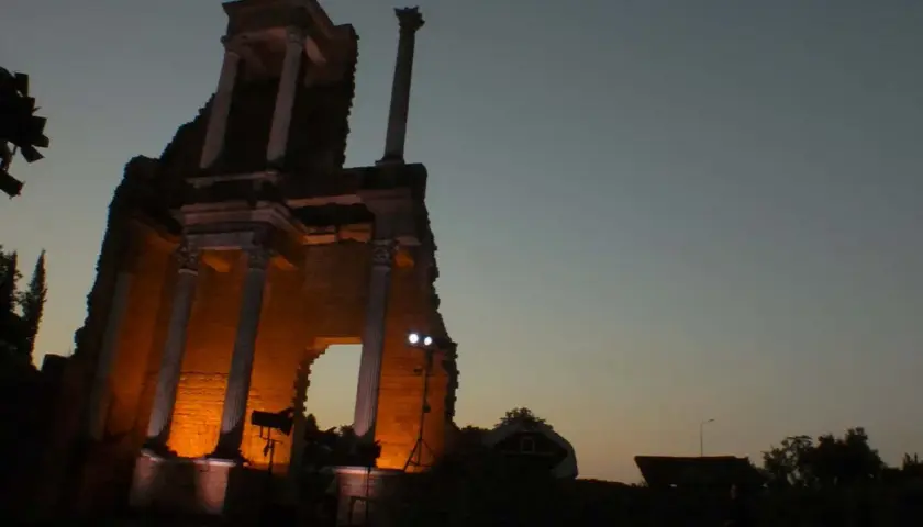 Il teatro romano di Volterra illuminato di sera, con le sue antiche colonne che emergono dall'ombra.