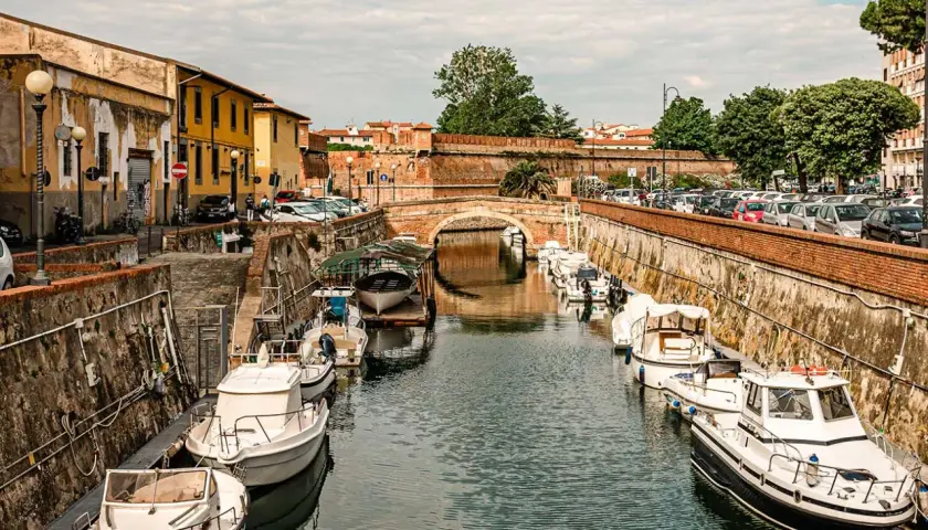 Canali di Livorno, un'ottima idea per cosa vedere in 2 giorni: barche ormeggiate lungo i muri di mattoni, un ponte ad arco e palazzi storici.