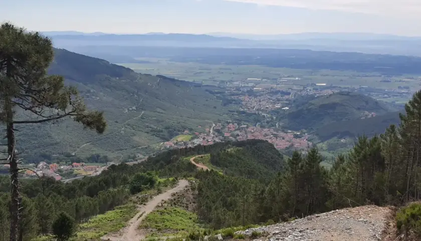 Panoramica mozzafiato con un sentiero tortuoso tra i pini, che conduce a un villaggio incastonato tra le colline. Buti cosa vedere in questo paesaggio incantevole.