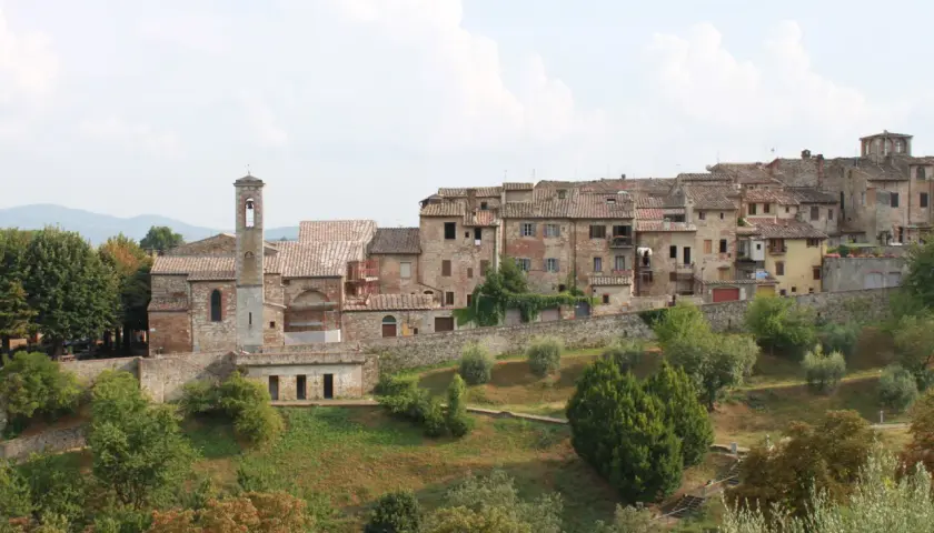 Panoramica di Colle Val d'Elsa, con le sue case in pietra e il campanile che svetta tra gli alberi verdi.