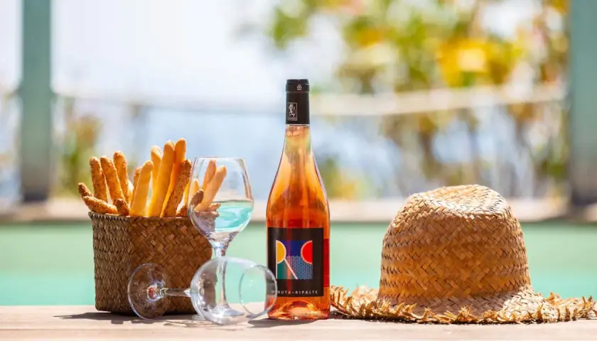 Un bicchiere di vino dolce dell'Elba, grissini croccanti e un cappello di paglia, perfetti per un aperitivo al mare.