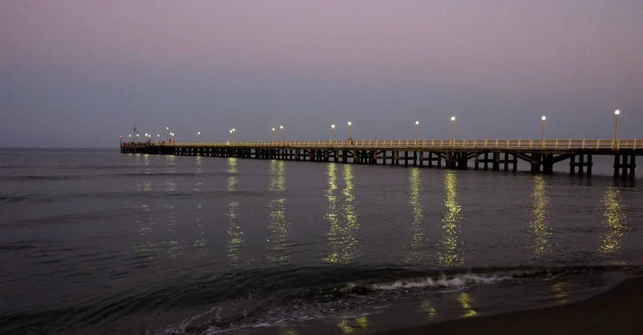 Il pontile di Forte dei Marmi illuminato al crepuscolo, con le luci che si specchiano sul mare calmo.