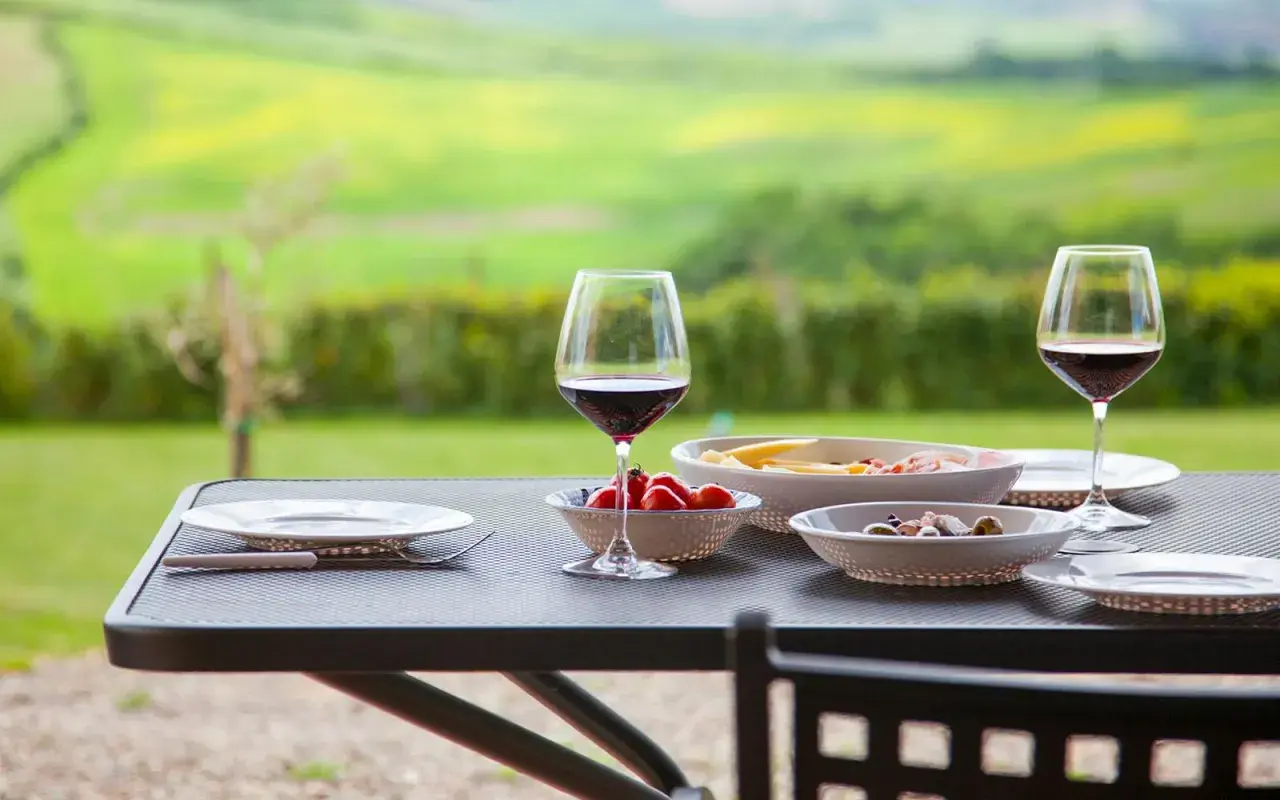 Un bicchiere di vino rosso e stuzzichini su un tavolo con vista sui chianti vineyards.
