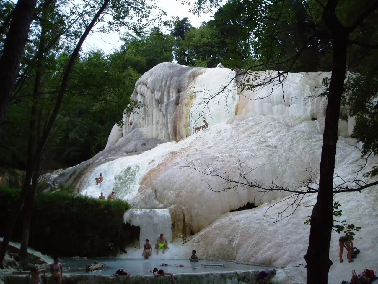 Cascate di travertino a Santa Fiora Terme, con persone che si rilassano nelle acque termali.