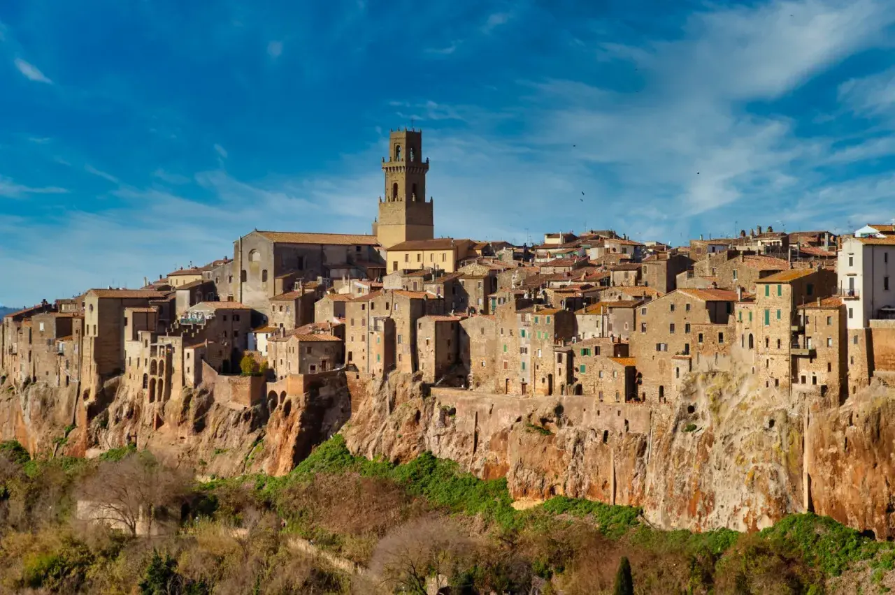 Il centro storico di Pitigliano, arroccato su una rupe tufacea, con le sue case antiche e la torre campanaria che domina il paesaggio.