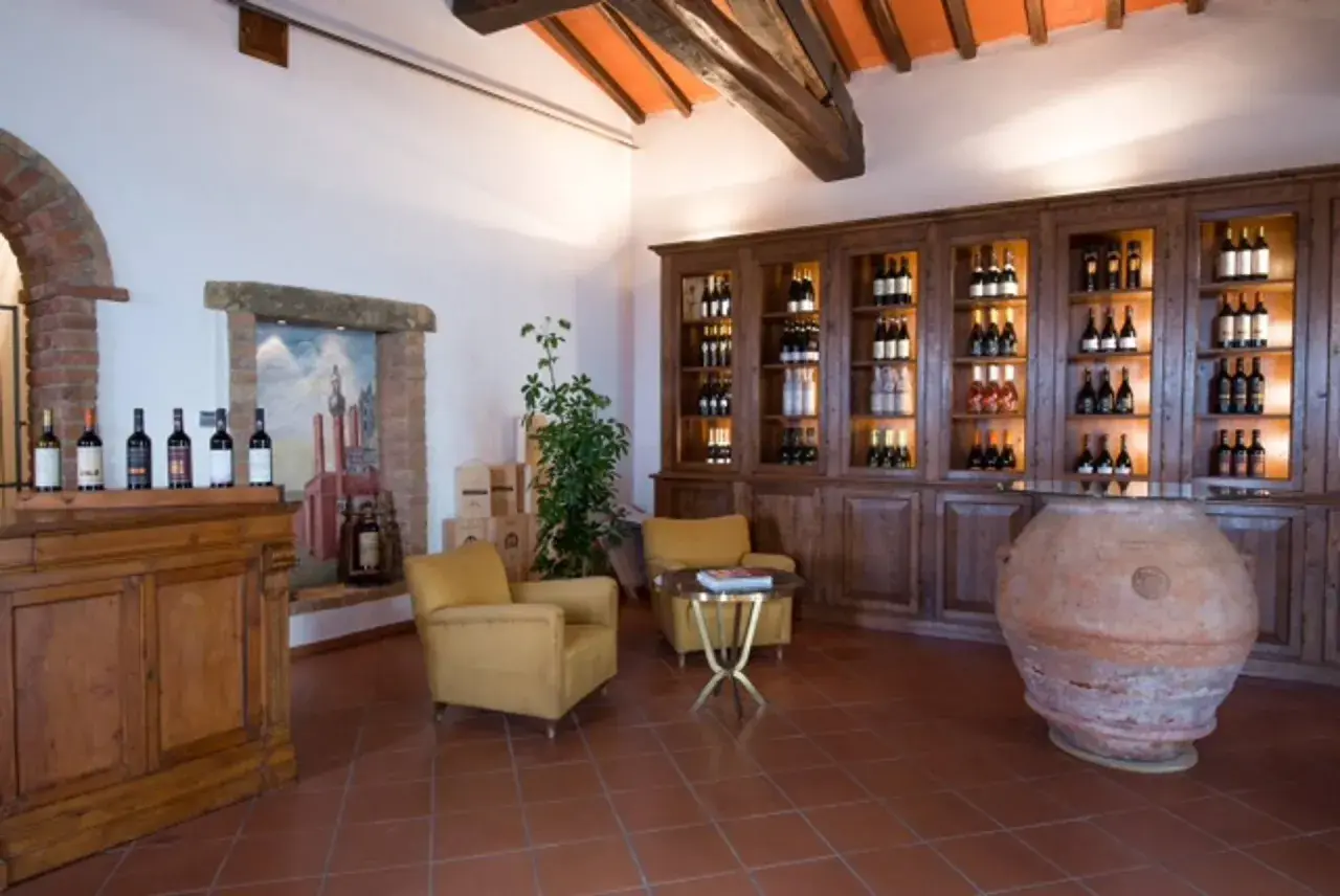 Interno accogliente della cantina Melini, con bottiglie di vino esposte su scaffali in legno e un'antica anfora.