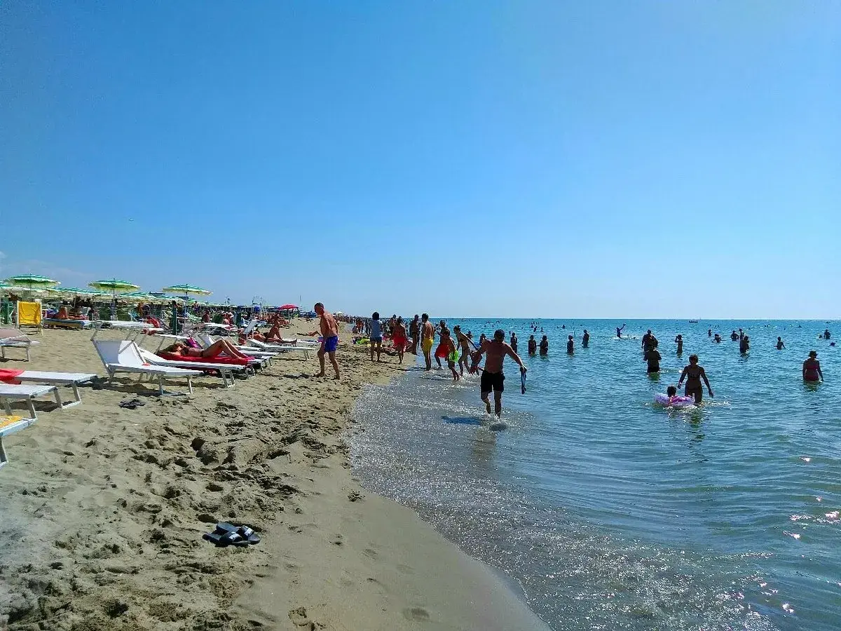 Una giornata di sole a Marina di Tirrenia, con bagnanti che si godono il mare e la spiaggia affollata di ombrelloni e lettini.