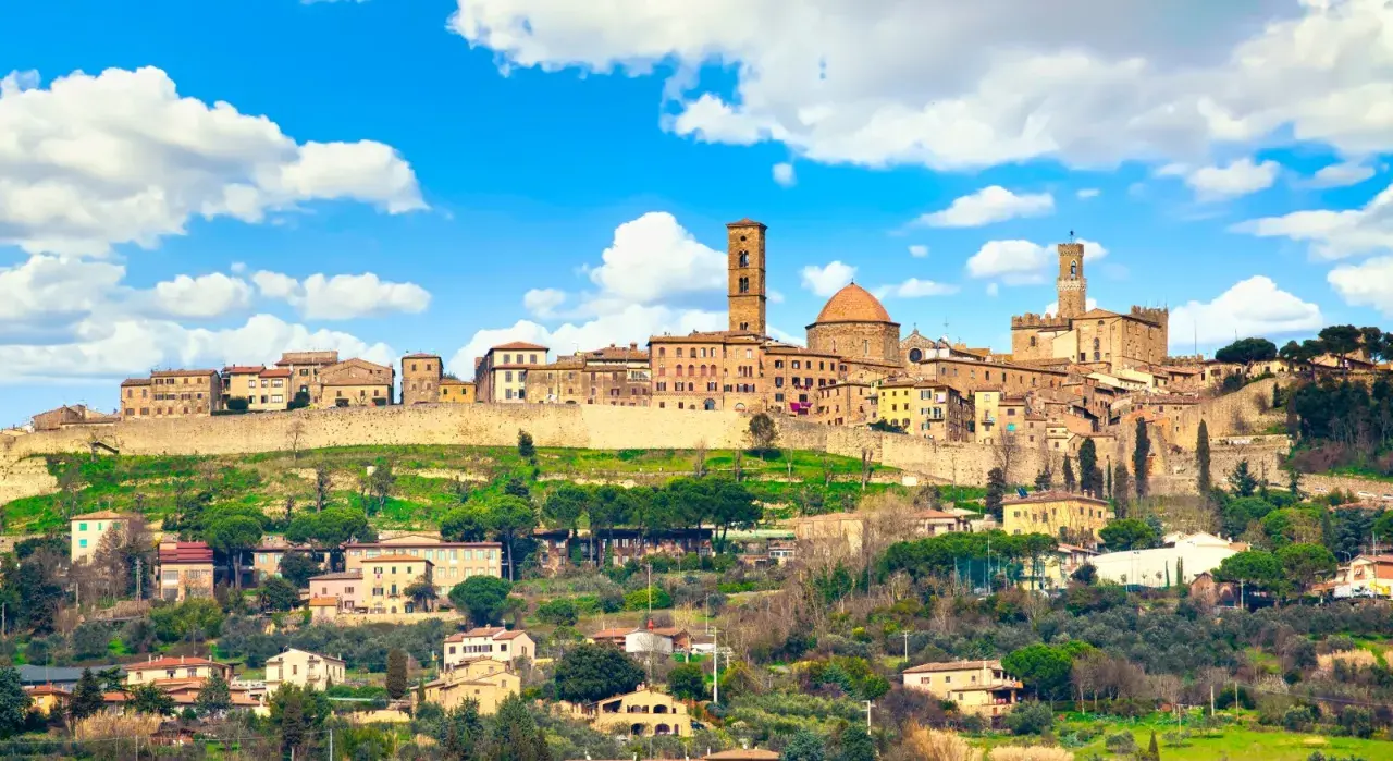 Panoramica di Volterra, con torri medievali e case in pietra su una collina verde. Molte cose da fare a Volterra, tra cui esplorare il centro storico.
