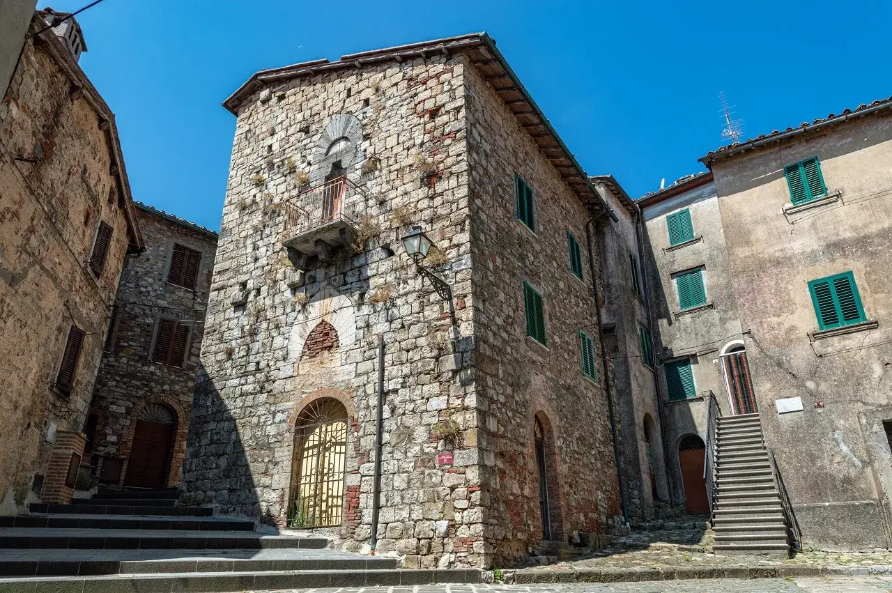 Antiche case in pietra a Montieri, cosa vedere: un vicolo con scale, balcone e finestre verdi.