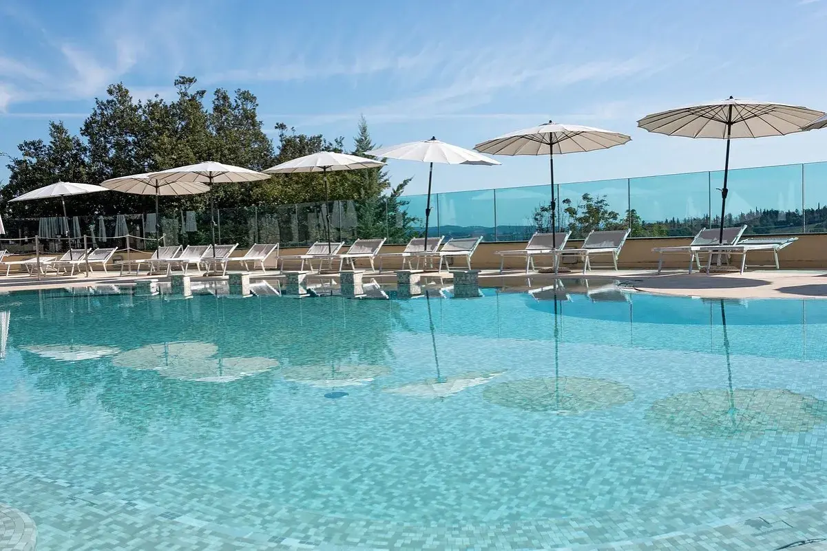 Piscina con lettini e ombrelloni, riflessi sull'acqua cristallina. Un angolo di relax a **Abbadia San Salvatore terme**.
