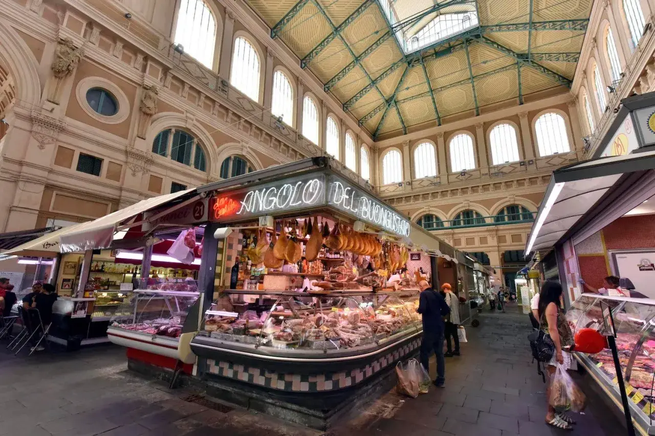 Mercato coperto con banchi di salumi e formaggi, un angolo del buon gusto tra i più bei mercati di Toscana.
