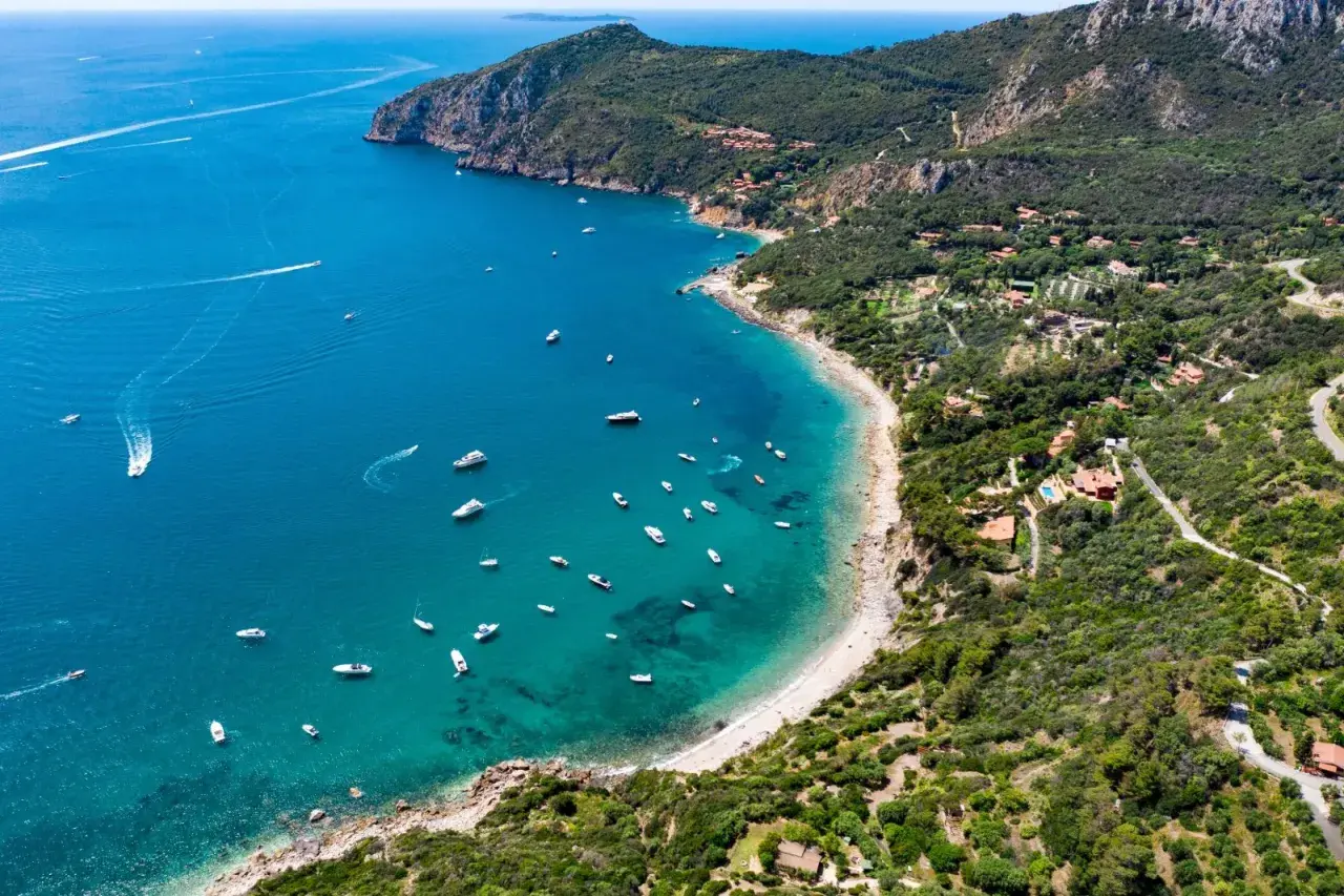 Baia con acque cristalline e numerose barche al largo di Porto Santo Stefano.