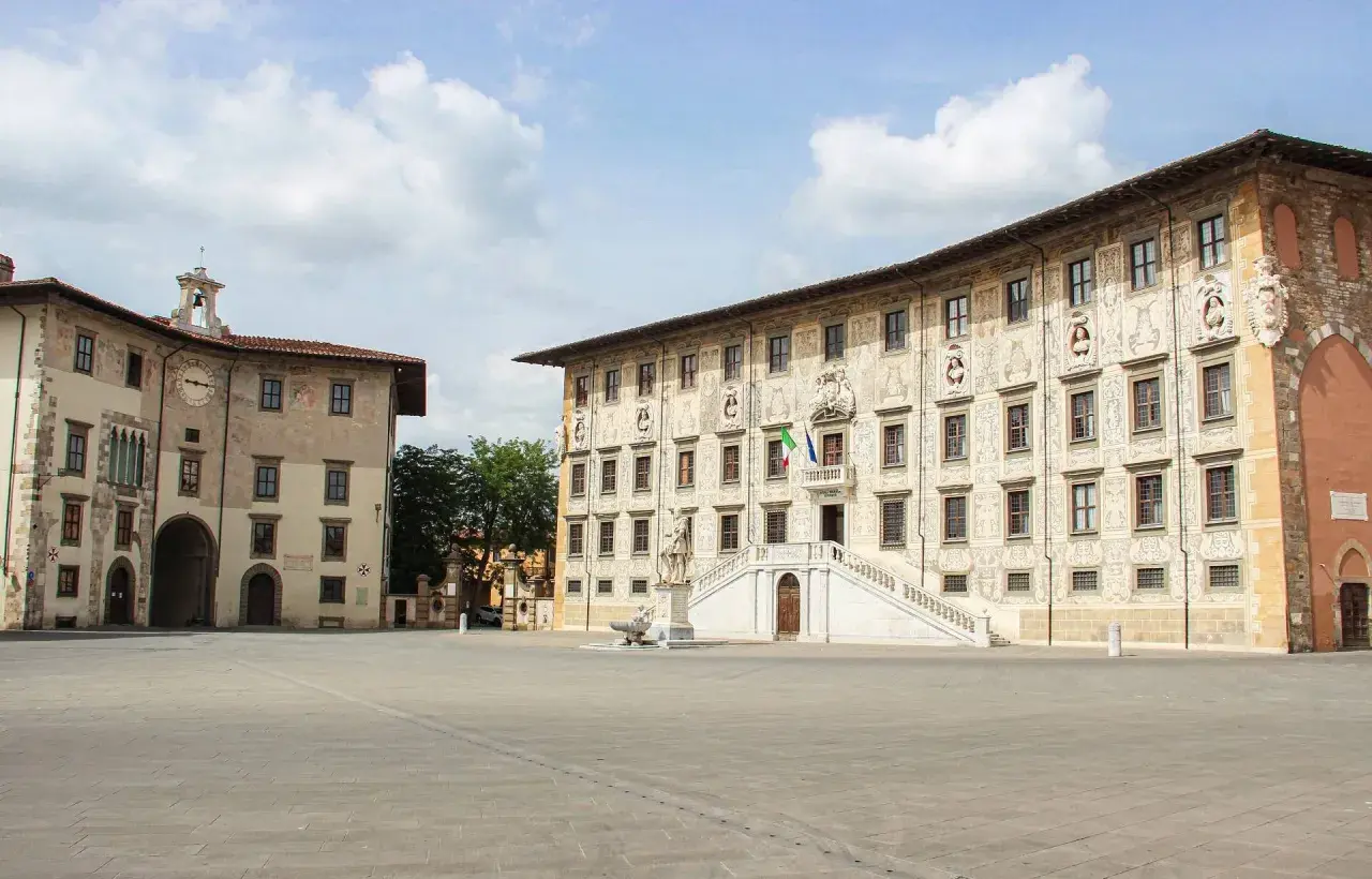 La **piazza dei Cavalieri** a Pisa, con i suoi palazzi storici e la scalinata monumentale, sotto un cielo nuvoloso.