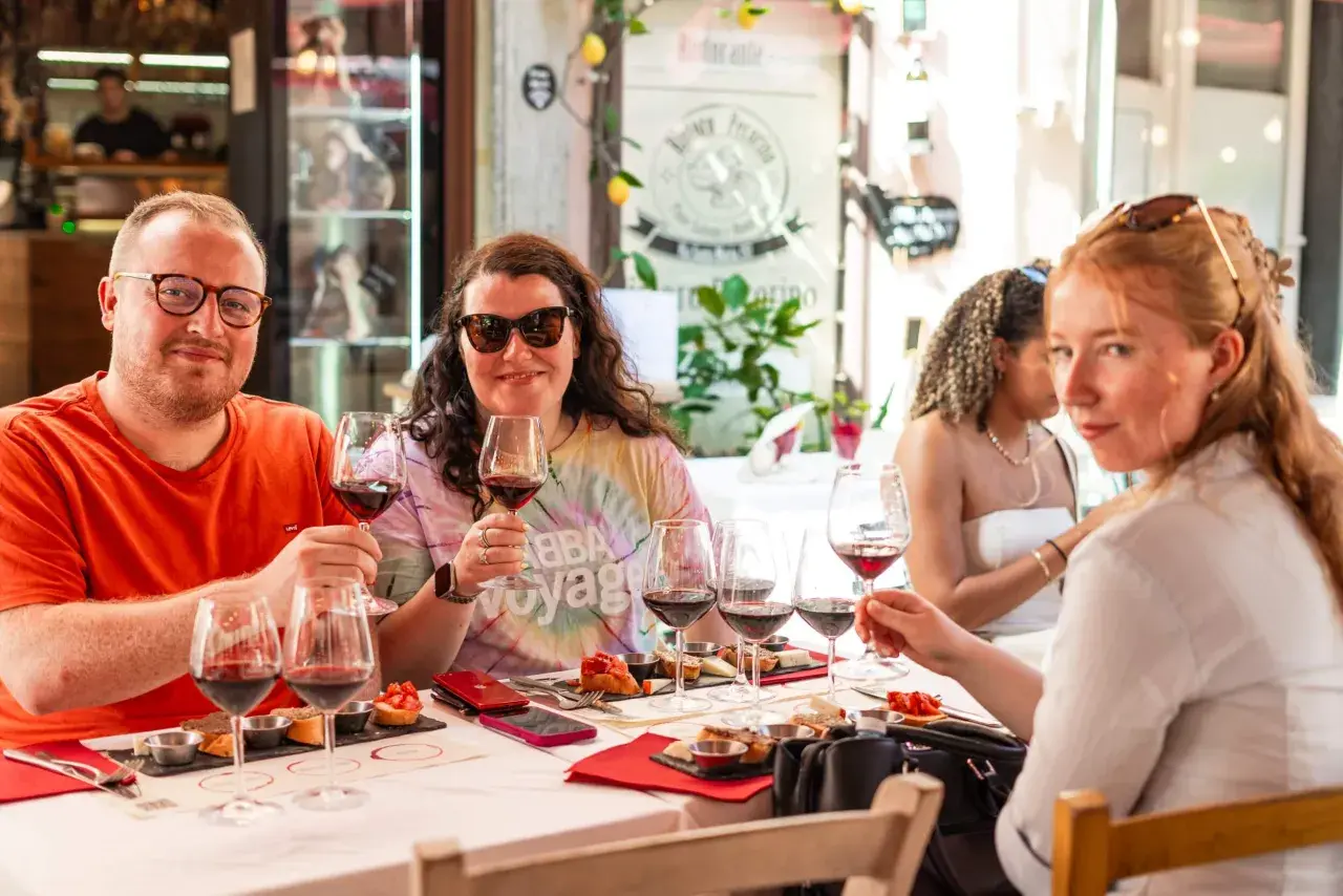 Amici brindano a una degustazione vini a Pisa, assaporando sapori toscani con un bicchiere di rosso.