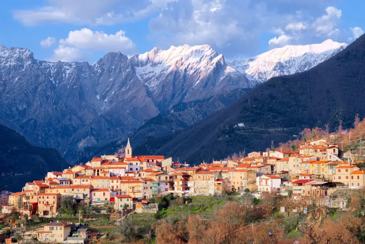 Borgo pittoresco alle pendici delle Alpi Apuane, con case dai tetti rossi e montagne innevate sullo sfondo. Un luogo incantevole da scoprire.