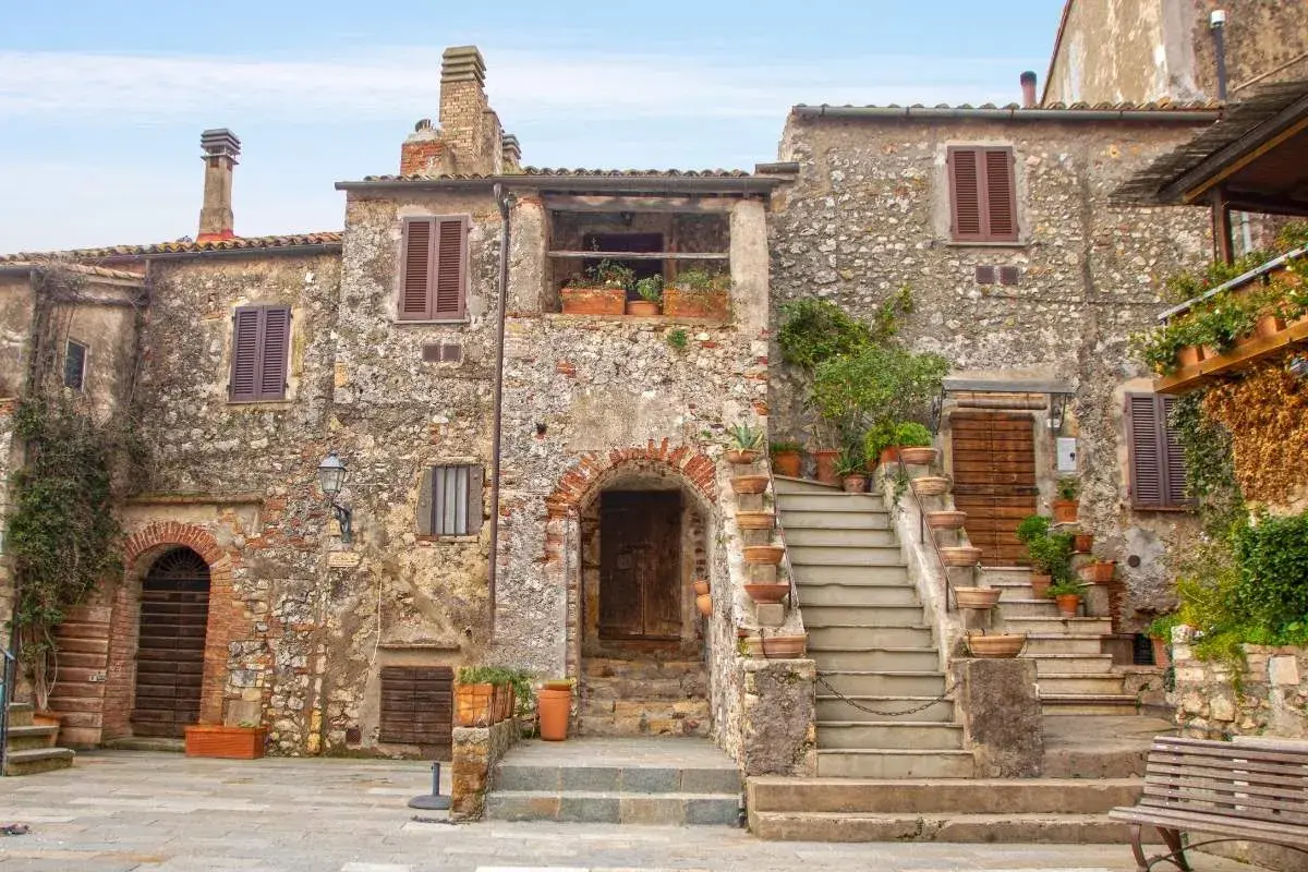 Un pittoresco borgo toscano con case in pietra, scale in terracotta e piante rigogliose.