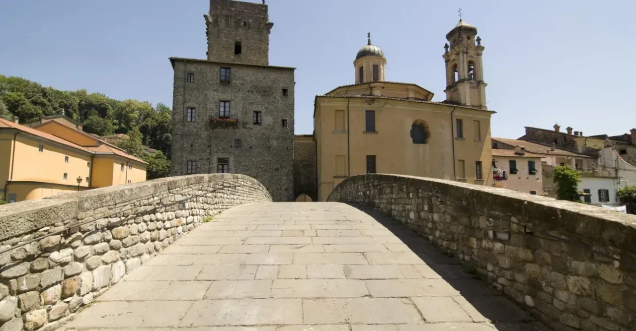 Ponte in pietra a Pontremoli, con torre medievale e campanile. Un luogo incantevole per scoprire cosa fare a Pontremoli.