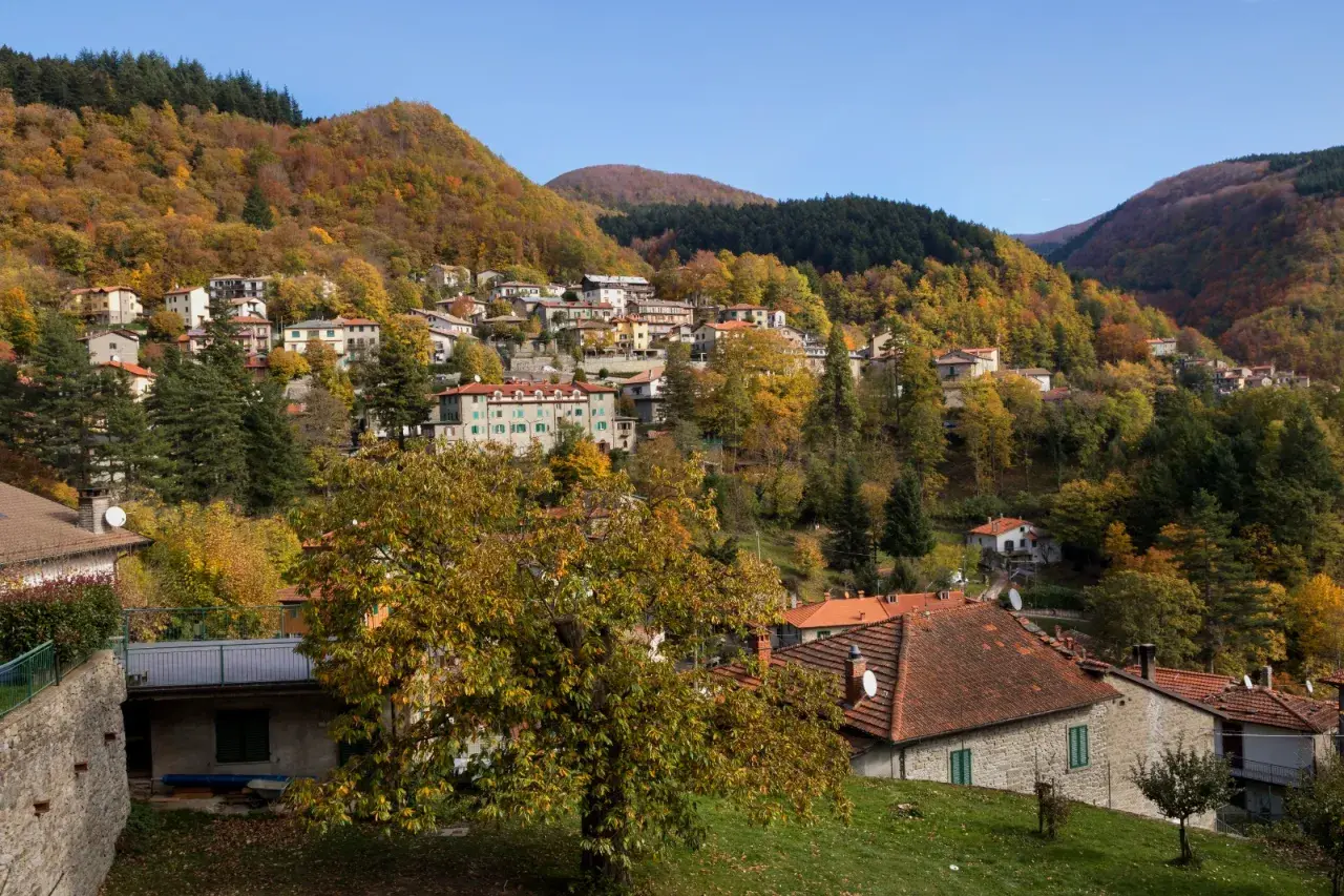 Case colorate e boschi autunnali abbracciano il borgo di Badia Prataglia, un incantevole paesaggio appenninico.