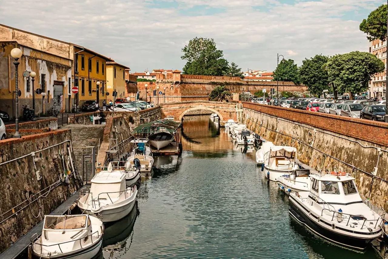 Canali di Livorno, un'ottima idea per cosa vedere in 2 giorni: barche ormeggiate lungo i muri di mattoni, un ponte ad arco e palazzi storici.