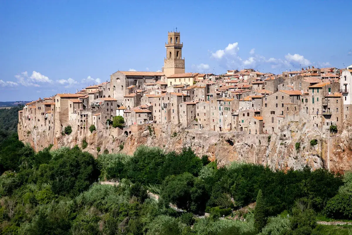Il centro storico di Pitigliano, arroccato su una rupe tufacea, domina il paesaggio con le sue case antiche e la torre campanaria.