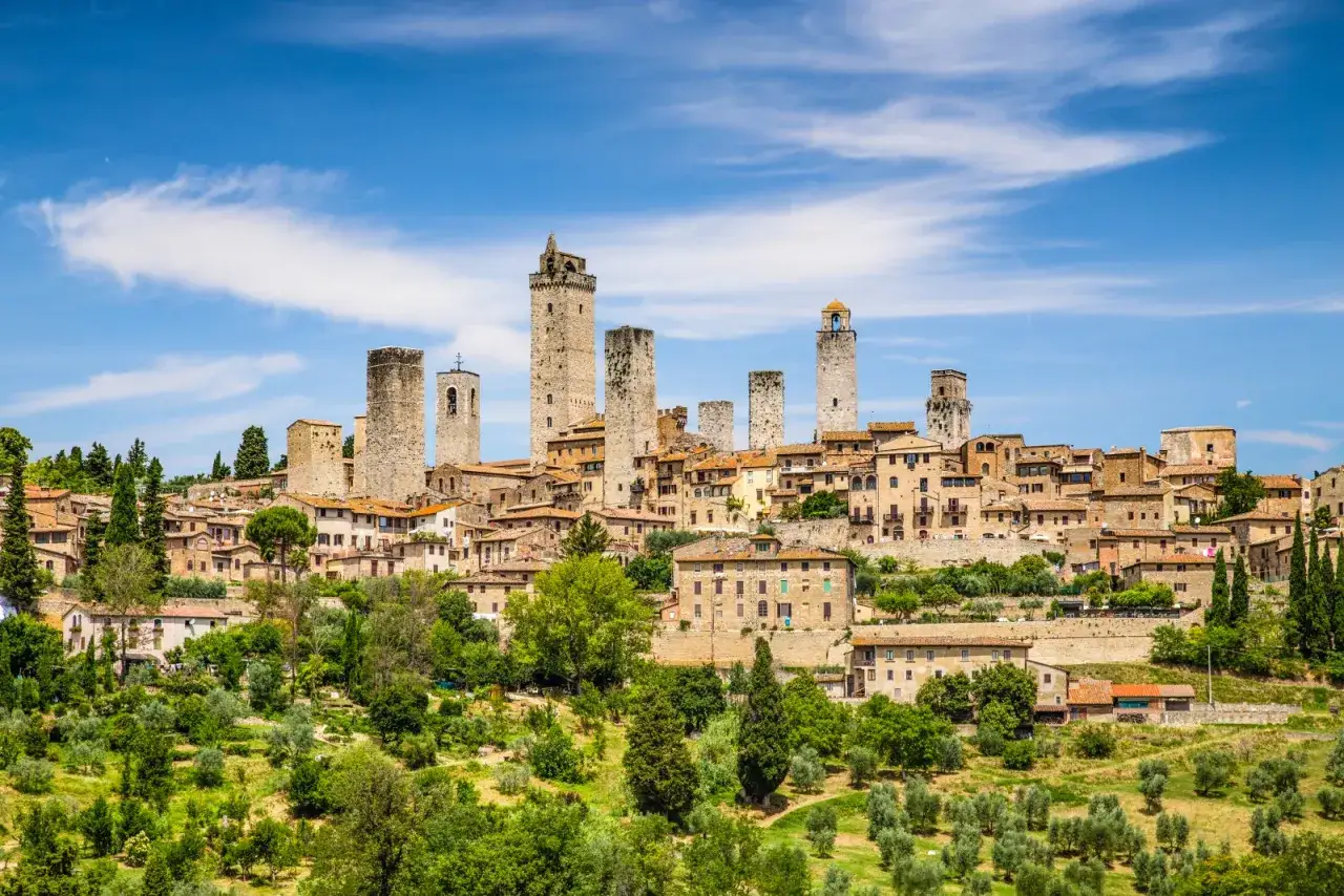 Panoramica di San Gimignano, con le sue iconiche torri medievali che svettano su un paesaggio collinare verdeggiante. Un incantevole esempio di borghi vicino San Gimignano.