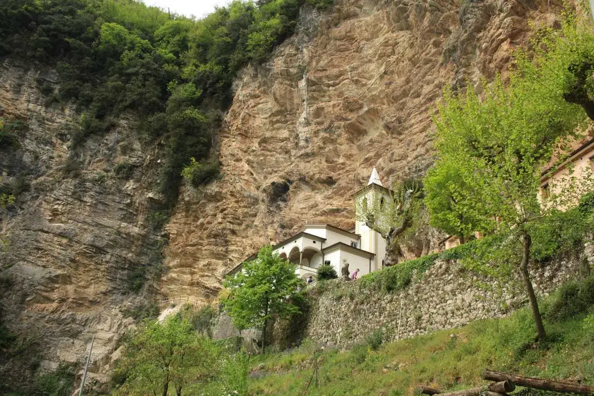 L'eremo di Calomini, incastonato nella roccia, con la sua chiesa e campanile, circondato dal verde.
