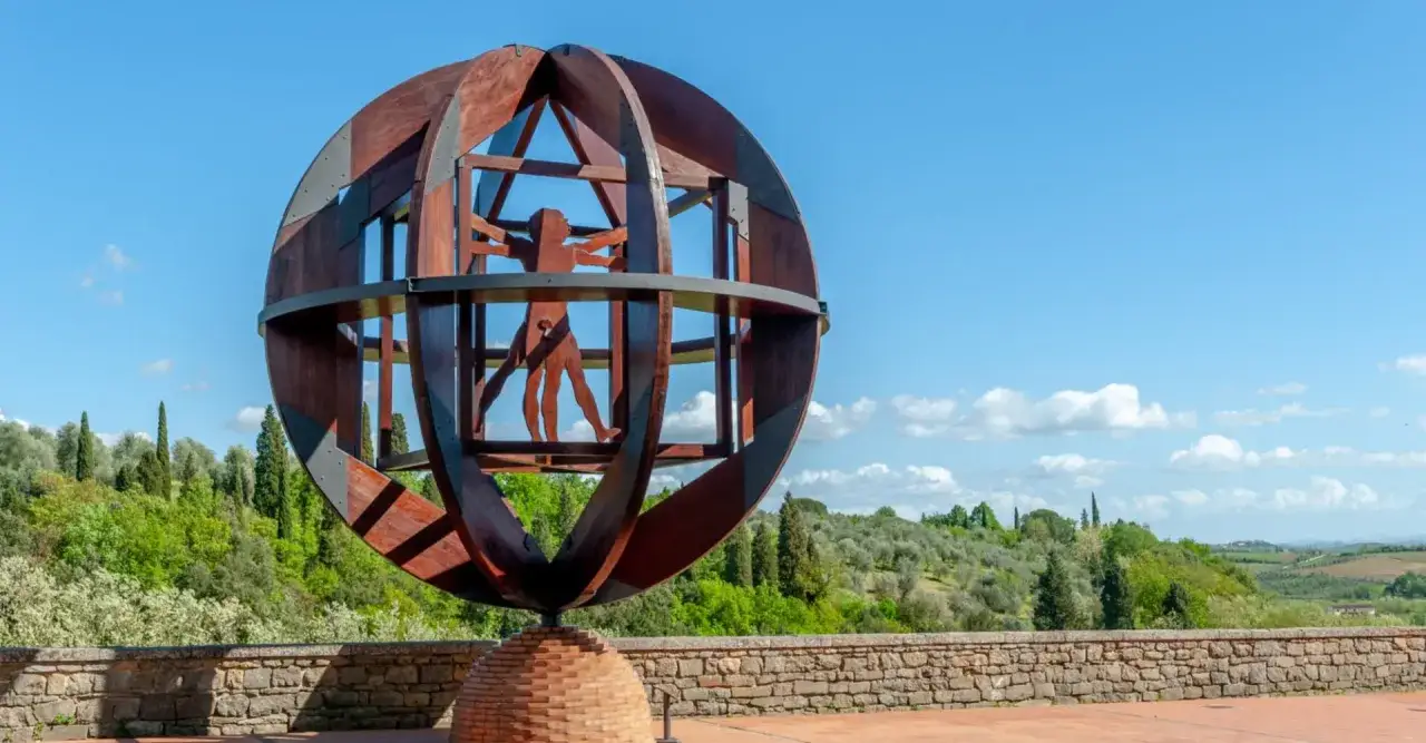 Statua dell'Uomo Vitruviano, un'icona di cosa vedere a Vinci, su uno sfondo di colline toscane.