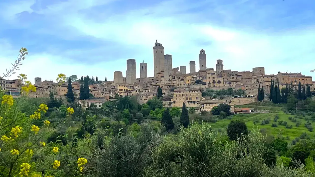 San Gimignano, con le sue torri medievali, appare come un gioiello nascosto tra colline verdi e fiori gialli. Scopri i suoi san gimignano geheimtipps.