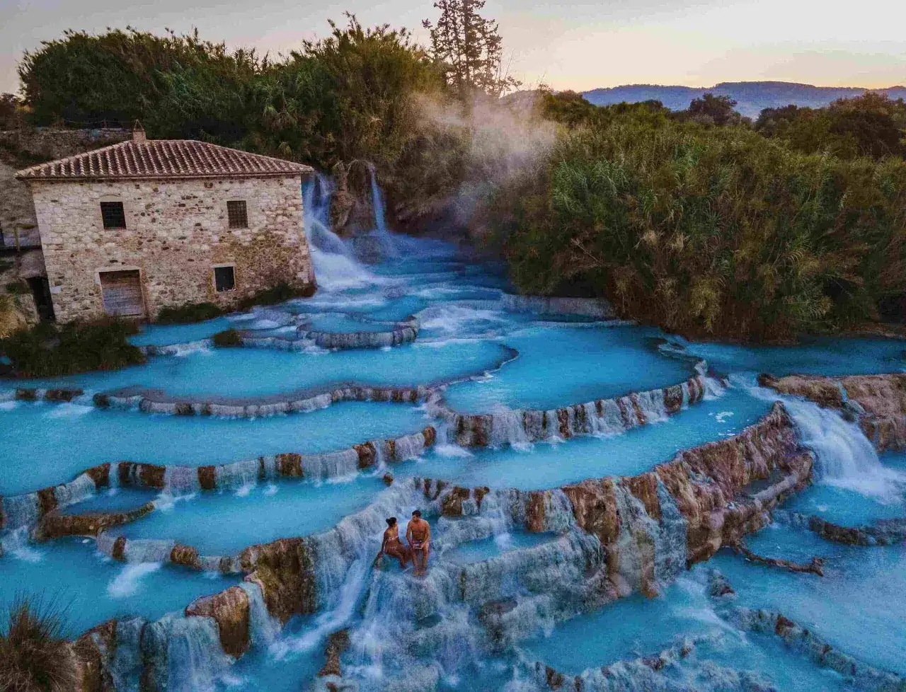 Cascate naturali di acqua turchese a Santa Fiora Terme, con una coppia che si gode il panorama.