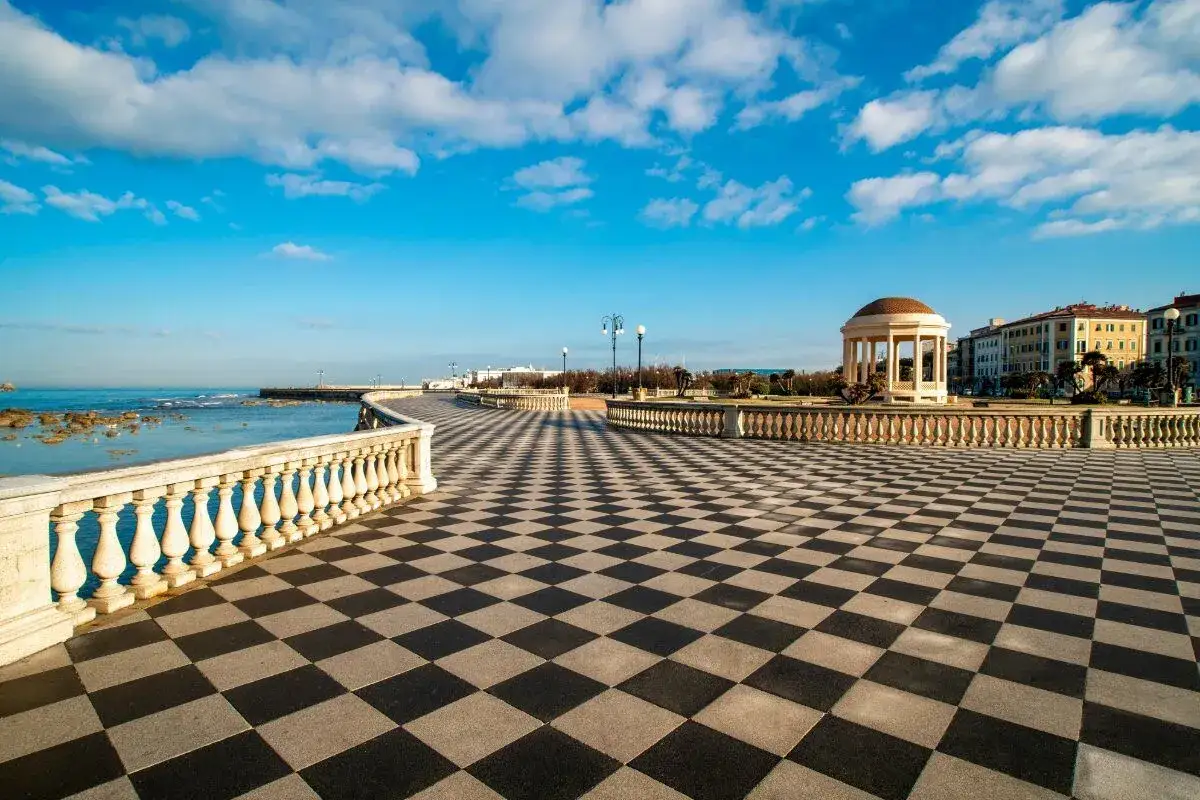 Il lungomare di Livorno con la sua iconica pavimentazione a scacchi, il mare azzurro e un gazebo neoclassico.