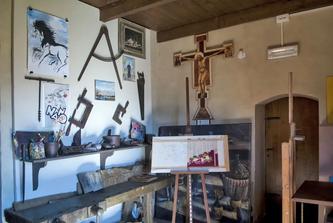 Interno di una bottega d'artista, forse la casa di Giotto, con crocefisso, tele, cavalletto, attrezzi da lavoro e opere appese.