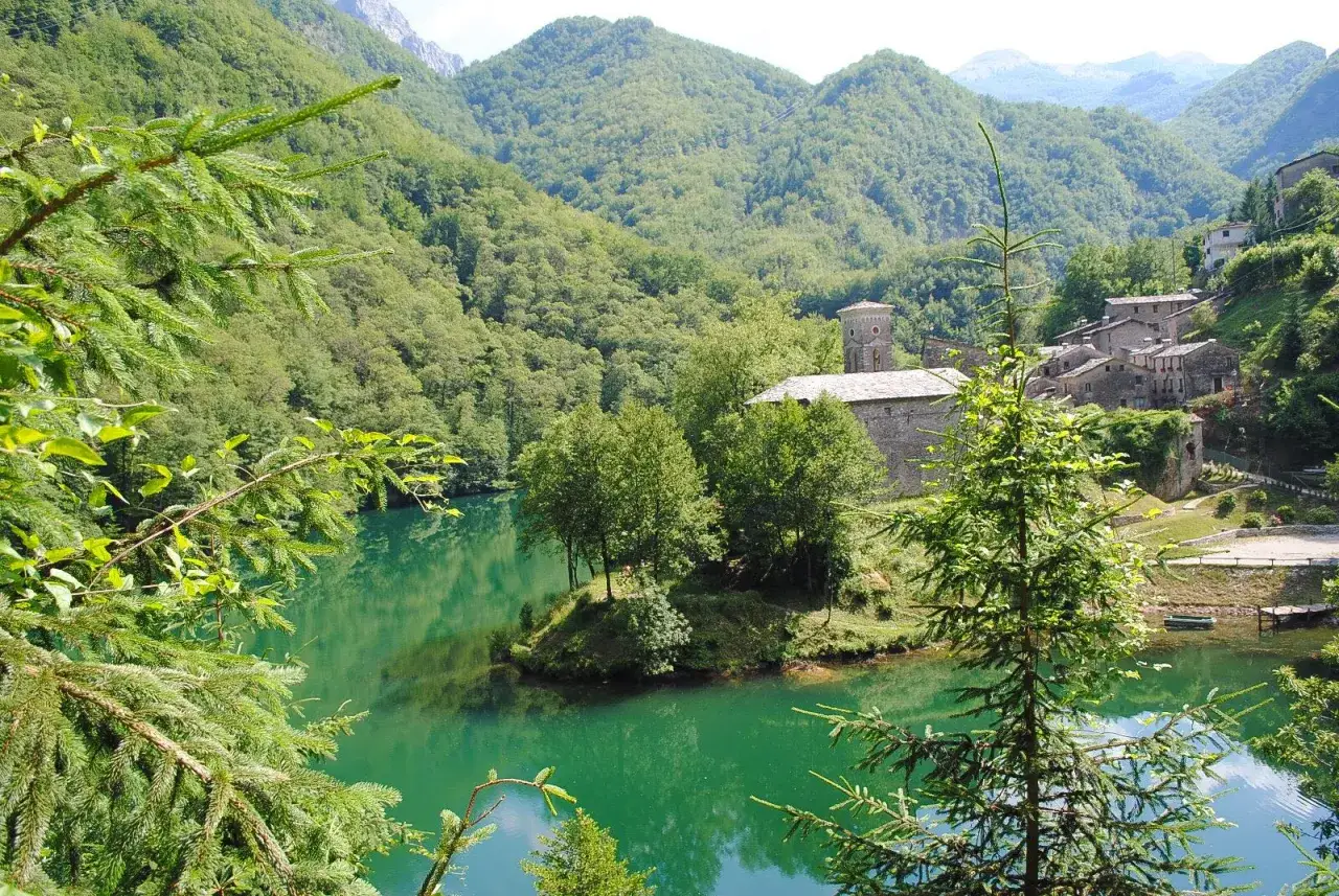 Un'isola verde nel lago turchese, con un borgo antico e la chiesa che si affacciano sulle Alpi Apuane. Un luogo incantevole, l'isola santa.