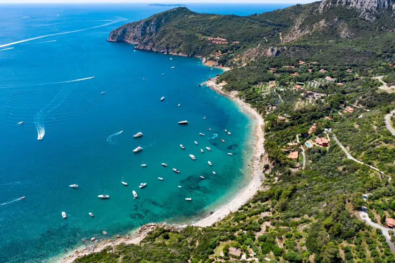 Baia con acque cristalline e numerose barche, incastonata tra colline verdi e ville isolate. Un angolo di paradiso tra le citt&agrave; toscane sul mare.