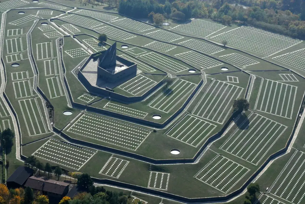 Vasta distesa di tombe bianche disposte in file ordinate, con un imponente monumento centrale. Il cimitero tedesco al Passo della Futa, un luogo di memoria.